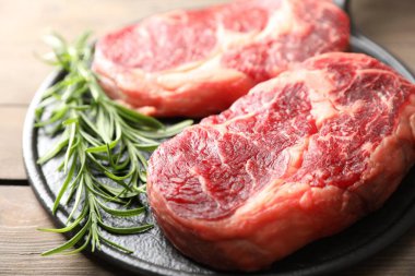 Çiğ et parçaları ve ahşap masada biberiye, yakın plan.