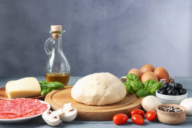 Pizza yapıyorum. Gri ahşap masadaki farklı malzemeler.