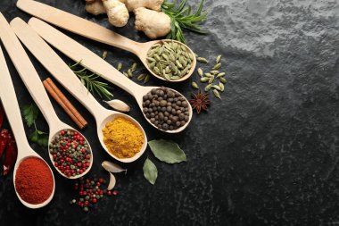 Siyah masadaki kaşıklarda bir sürü farklı baharat var. Metin için boşluk