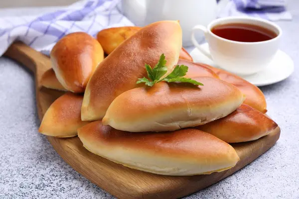 Lezzetli fırında köfteler ve bir fincan çay. Gri desenli masa, yakın plan.