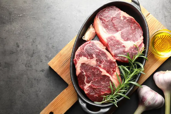 Fırın kabında baharatlı çiğ et parçaları ve gri desenli masa üzerinde de yağ. Metin için boşluk