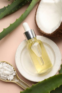 Saç tedavisi. Kozmetik ürünler, hindistan cevizi, tereyağı talaşı ve bej arka planda aloe yaprakları, düz yatış