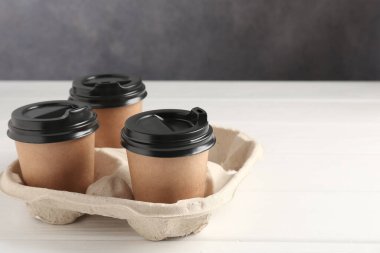 Kağıt kahve bardakları beyaz ahşap masadaki karton tutacakta. Metin için boşluk