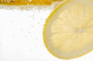 Arka planda limon dilimleri olan soda, yakın plan.