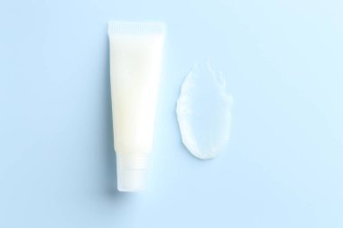 Açık mavi arkaplanda nemlendirici dudak kremi ve tüp, üst görünüm