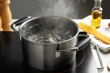 Kaynar suyla pişirme tenceresi ve beyaz masa üzerinde gri arka plan, yakın çekim