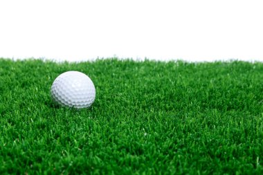Beyaz arka plana karşı yeşil çimlerde golf topu