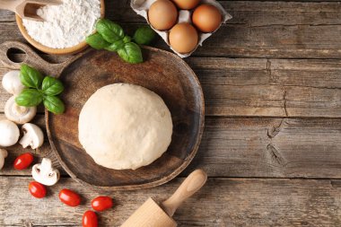 Pizza yapıyorum. Tahta masadaki farklı malzemeler, düz yatış. Metin için boşluk