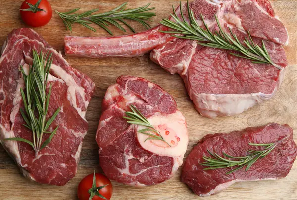 Tahta masada çiğ et, biberiye ve domates parçaları.