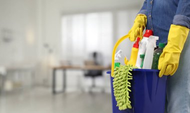 Ofisinde farklı temizlik malzemeleri ve ürünleri olan bir kadın, yakın plan. Metin için pankart tasarımı ve boşluk