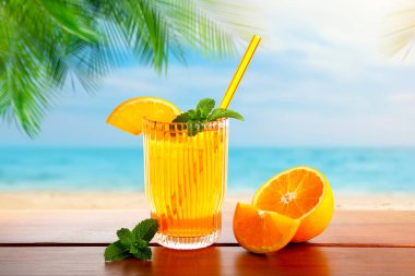 Tahta güvertede, yeşil palmiye yapraklarının altında güneşli tropik plajda ferahlatıcı bir kokteyl.