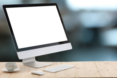 Boş ekranlı bilgisayar monitörü ve bulanık arka planda tahta masanın üzerinde fincan. Tasarım için model