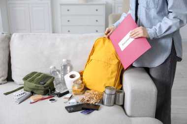 Hayatta kalma kiti. Evrakları sırt çantasına koyan kadın, yakın plan.