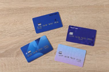 Çevrimiçi ödeme. Tahta masada, düz yerde farklı kredi kartları var.