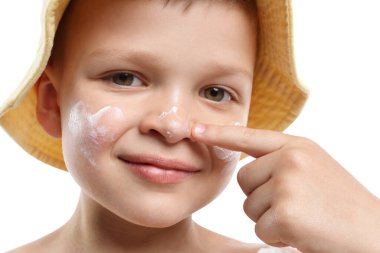 Küçük çocuk beyaz arka planda cildine güneş kremi sürüyor.