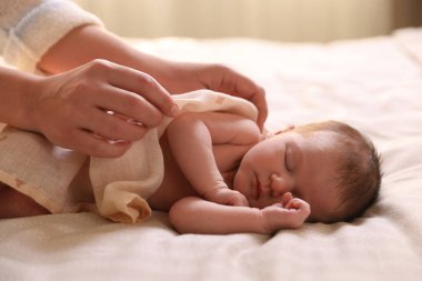 Yatma vakti. Anne uyuyan bebeğini battaniyeyle örtüyor.