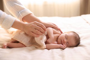 Yatma vakti. Anne uyuyan bebeğini battaniyeyle örtüyor.