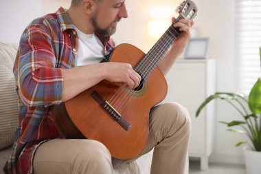 Evdeki kanepede gitar çalan adam.