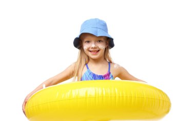 Cildinde güneş kremi ve beyaz arka planda şişme yüzük olan gülümseyen küçük bir kız.