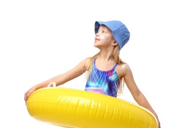 Cildinde güneş kremi ve beyaz arka planda şişme yüzük olan gülümseyen küçük bir kız.