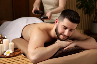 Adam spa salonunda taşlarla masaj yaptırıyor.