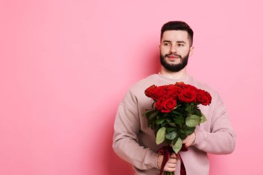 Pembe arka planda kırmızı gül buketi olan adam, metin için boşluk.