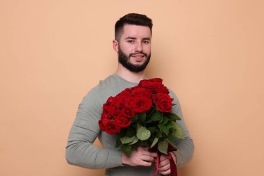 Bej arka planda kırmızı gül buketi olan mutlu adam.