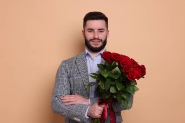 Bej arka planda kırmızı gül buketi olan mutlu adam.