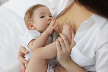 Anne, bebeğini evde yatakta emziriyor.