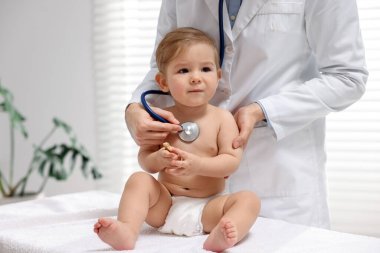 Pediyatrist klinikte küçük şirin bir bebeği muayene ediyor.