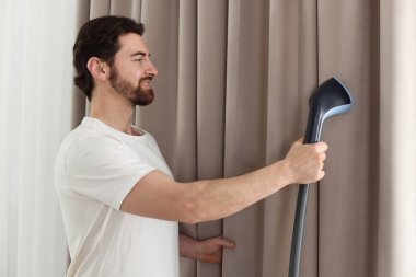 Evde buharlı perdeleri olan bir adam.