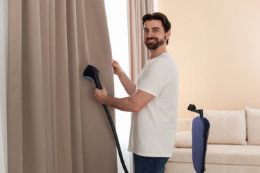 Evde buharlı perdeleri olan bir adam.