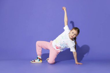 Mor arka planda dans eden şık elbiseli bir kız.