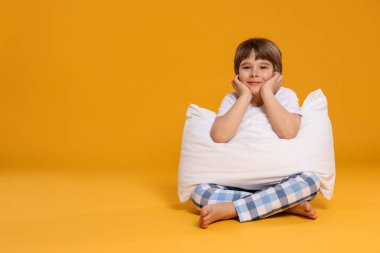 Turuncu arka planda yastığı olan tatlı bir çocuk. Metin için boşluk