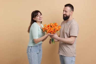 Adam bej arka planda sevgili karısına güzel laleler sunuyor.