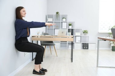 Ofiste duvar kenarında egzersiz yapan güzel bir kadın.