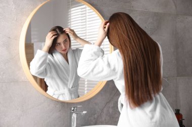 Banyoda aynanın yanında sağlıklı saç kökleri olan güzel bir kadın.