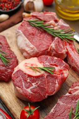 Çiğ et, biberiye ve domates parçaları ahşap masada, yakın plan.