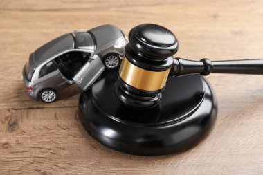 Trafik kazası yasası. Hakimin tokmağı ve oyuncak arabası ahşap masada, yakın plan.