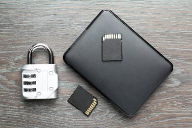 Sabit disk, SD hafıza kartları ve gri ahşap masa üzerindeki asma kilit kombinasyonu düz konum