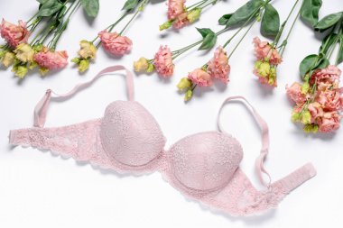 Beyaz arka planda pembe dantel sütyen ve Eustoma çiçekleri.