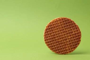 Yeşil arka planda lezzetli yuvarlak bir waffle. Metin için boşluk