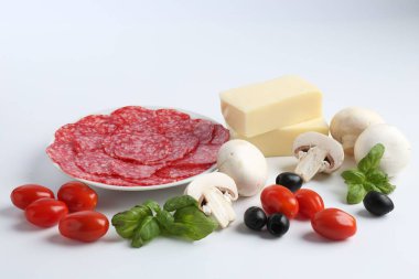 Pizza yapıyorum. Farklı malzemeler beyaza izole edilmiş.