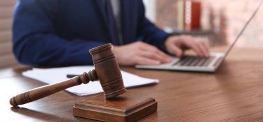 Tahta masada dizüstü bilgisayarda çalışan yargıca yakın çekim, tokmağa odaklan. Pankart tasarımı