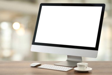 Boş ekranlı bilgisayar monitörü ve bulanık arka planda tahta masanın üzerinde fincan. Tasarım için model