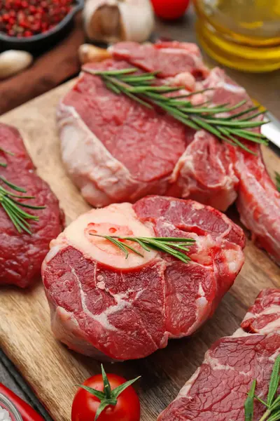 Çiğ et, biberiye ve domates parçaları ahşap masada, yakın plan.