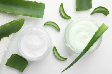 Aloe vera özütüyle nemlendirici krem ve beyaz desenli arka planda yapraklar.