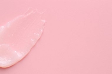 Pembe arka planda nemlendirici dudak kremi, üst manzara. Metin için boşluk