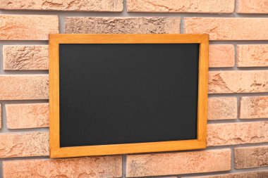 Tuğla duvarda boş küçük bir tahta.