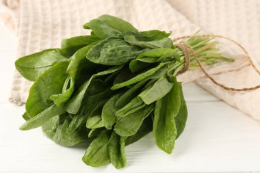 Beyaz ahşap masada taze yeşil kuş yaprakları, yakın plan.